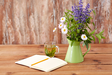 Image showing herbal tea, notebook and flowers in jug on table