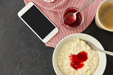 Image showing porridge with jam, spoon, coffee and phone