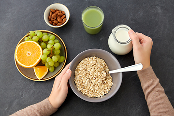 Image showing hands with oatmeal, fruits, nuts, juice and milk