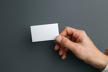 Image showing Male hand holding a blank business card on grey background for text or design