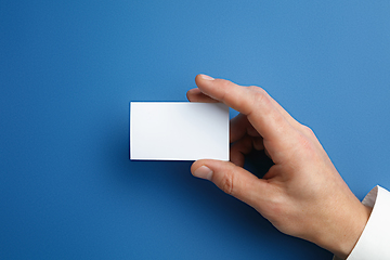 Image showing Male hand holding a blank business card on blue background for text or design