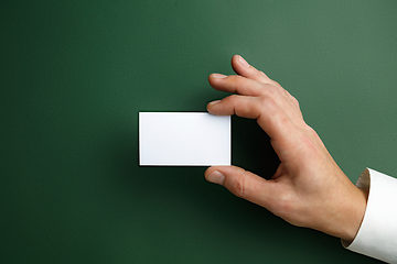 Image showing Male hand holding a blank business card on green background for text or design