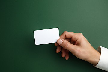 Image showing Male hand holding a blank business card on green background for text or design