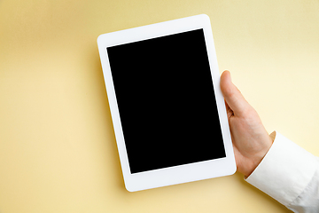 Image showing Male hand holding tablet with empty screen on yellow background for text or design