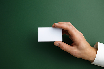 Image showing Male hand holding a blank business card on green background for text or design