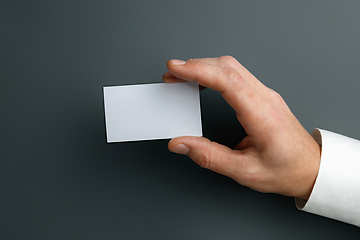 Image showing Male hand holding a blank business card on grey background for text or design