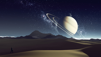 Image showing desert planet with explorer and saturn at the horizon