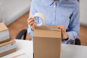 Image showing woman packing parcel box with adhesive tape