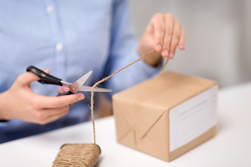 Image showing woman with parcel cutting rope at post office