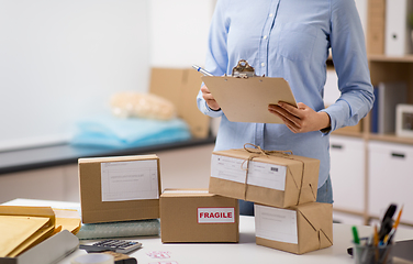 Image showing woman with parcels and clipboard at post office