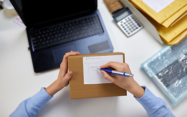 Image showing close up of hands filling form on parcel at office