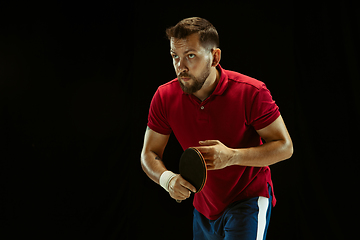 Image showing Young man playing table tennis on black studio background