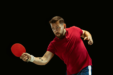 Image showing Young man playing table tennis on black studio background