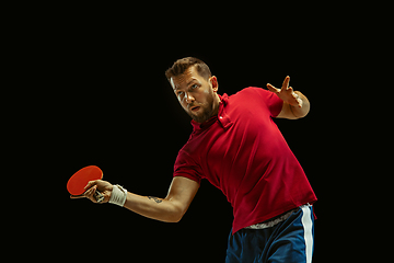 Image showing Young man playing table tennis on black studio background