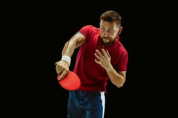 Image showing Young man playing table tennis on black studio background