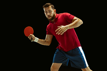 Image showing Young man playing table tennis on black studio background