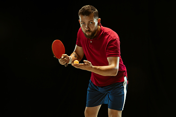 Image showing Young man playing table tennis on black studio background