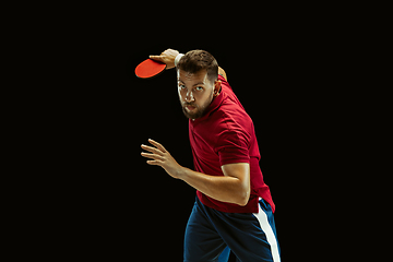 Image showing Young man playing table tennis on black studio background