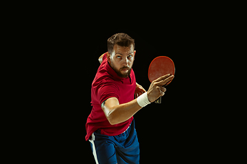 Image showing Young man playing table tennis on black studio background