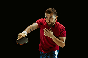 Image showing Young man playing table tennis on black studio background