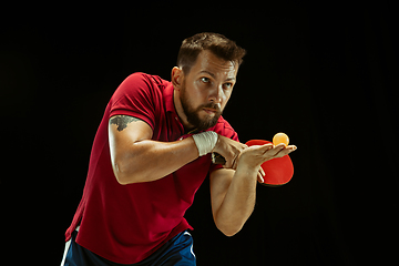 Image showing Young man playing table tennis on black studio background