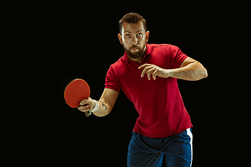 Image showing Young man playing table tennis on black studio background
