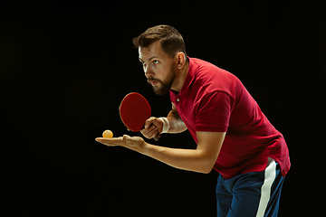 Image showing Young man playing table tennis on black studio background