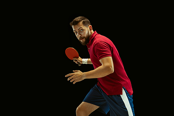 Image showing Young man playing table tennis on black studio background