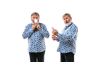 Image showing Senior man arguing with himself on white studio background.