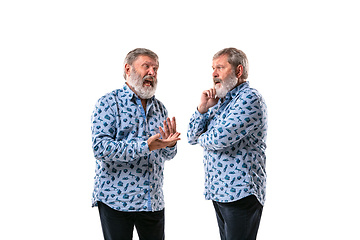 Image showing Senior man arguing with himself on white studio background.