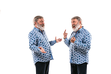 Image showing Senior man arguing with himself on white studio background.