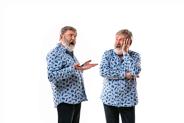 Image showing Senior man arguing with himself on white studio background.