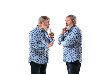 Image showing Senior man arguing with himself on white studio background.