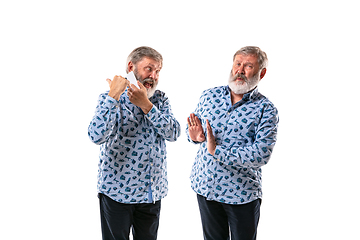 Image showing Senior man arguing with himself on white studio background.