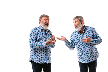 Image showing Senior man arguing with himself on white studio background.