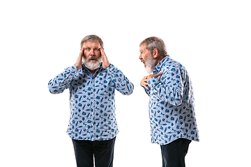 Image showing Senior man arguing with himself on white studio background.