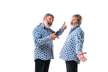 Image showing Senior man arguing with himself on white studio background.