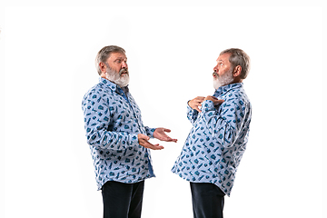 Image showing Senior man arguing with himself on white studio background.