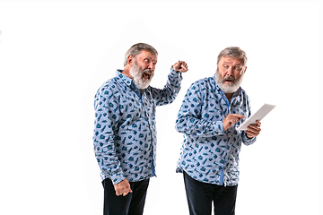 Image showing Senior man arguing with himself on white studio background.