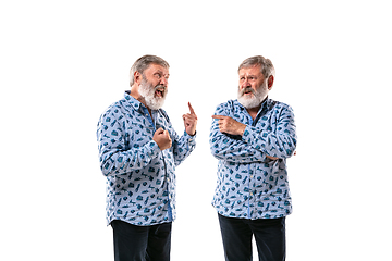 Image showing Senior man arguing with himself on white studio background.