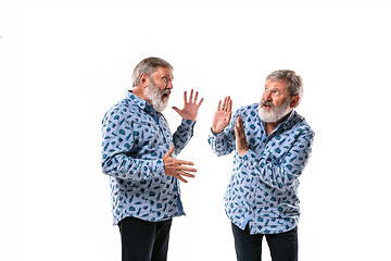 Image showing Senior man arguing with himself on white studio background.