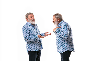 Image showing Senior man arguing with himself on white studio background.