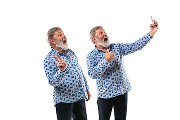 Image showing Senior man arguing with himself on white studio background.