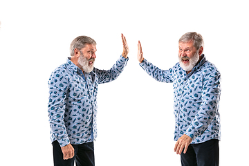 Image showing Senior man arguing with himself on white studio background.