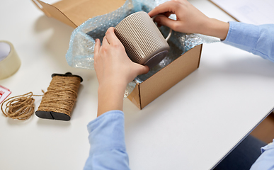 Image showing hands packing mug to parcel box at post office