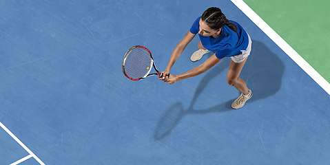 Image showing Young woman in blue shirt playing tennis. Youth, flexibility, power and energy.