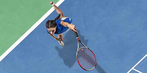 Image showing Young woman in blue shirt playing tennis. Youth, flexibility, power and energy.