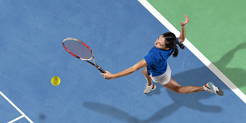 Image showing Young woman in blue shirt playing tennis. Youth, flexibility, power and energy.