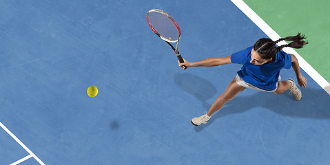 Image showing Young woman in blue shirt playing tennis. Youth, flexibility, power and energy.