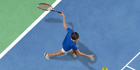 Image showing Young woman in blue shirt playing tennis. Youth, flexibility, power and energy.